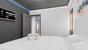 A modern hotel room with a large bed, a flat-screen TV mounted on the wall, and a door leading to another room. - Cozy 2-bedroom apartment in beautiful București with AC (București)