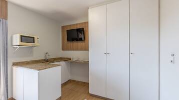 Una cocina equipada con microondas, televisor y lavamanos.