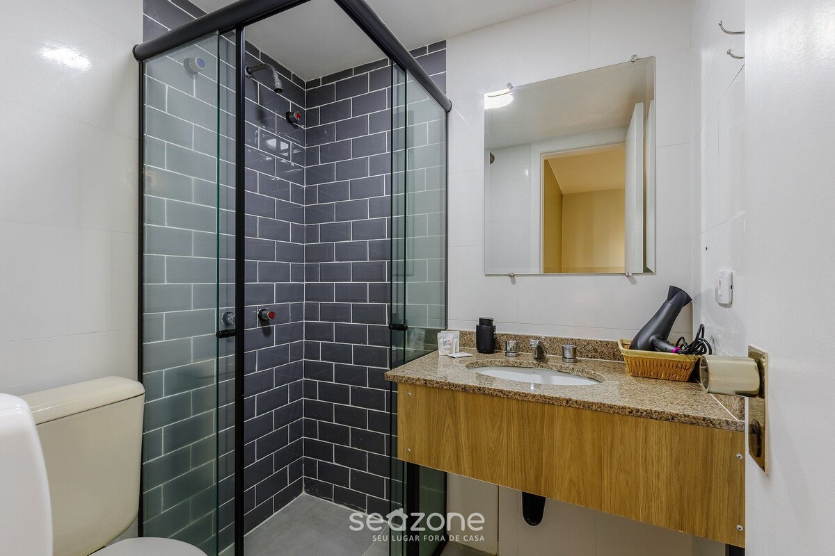 Une salle de bain avec une douche à parois de verre, des toilettes, un lavabo avec un miroir et un porte-serviettes.
