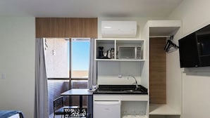 Una kitchenette compacta equipada con microondas, cafetera y un refrigerador pequeño.