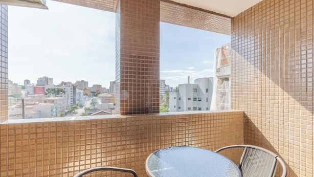Un balcón con paredes de baldosas, una mesa y sillas, con vistas a un paisaje urbano con varios edificios.
