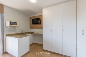 Ett kök med mikrovågsugn, TV och diskho.