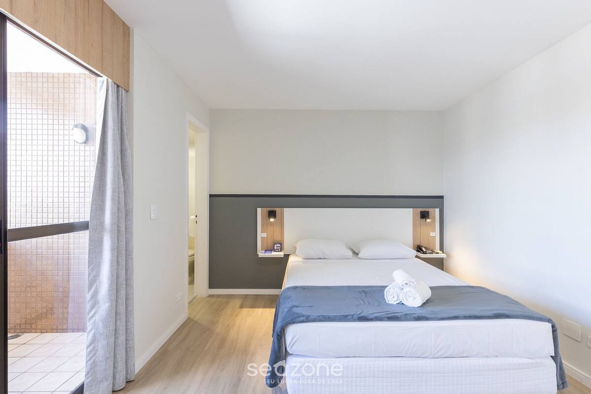 Een moderne hotelkamer met een groot bed, een klein nachtkastje en een inbouwplank.