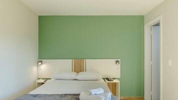 Uma cama de solteiro com cabeceira, mesas de cabeceira e uma parede verde.
