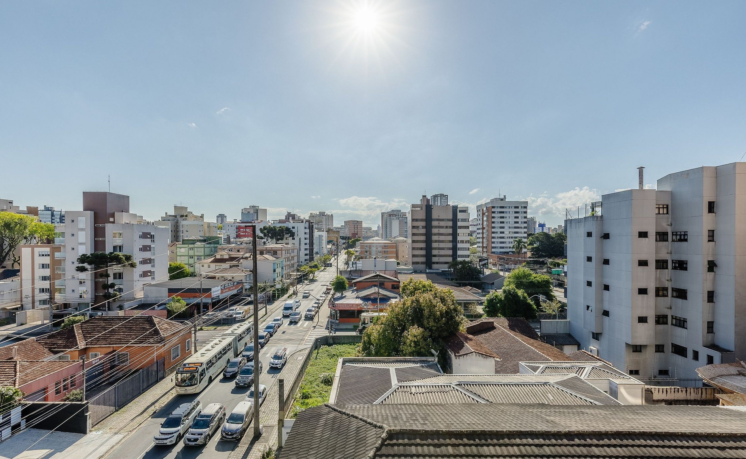 A cityscape with modern and traditional buildings, a clear sky, and a street with cars and a bus.