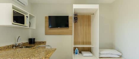 A modern bathroom with a granite countertop, sink, and a mounted television.