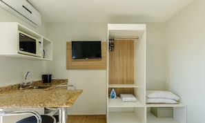 A modern bathroom with a granite countertop, sink, and a mounted television. - Studios at Upper Residence - Upps II (Curitiba)