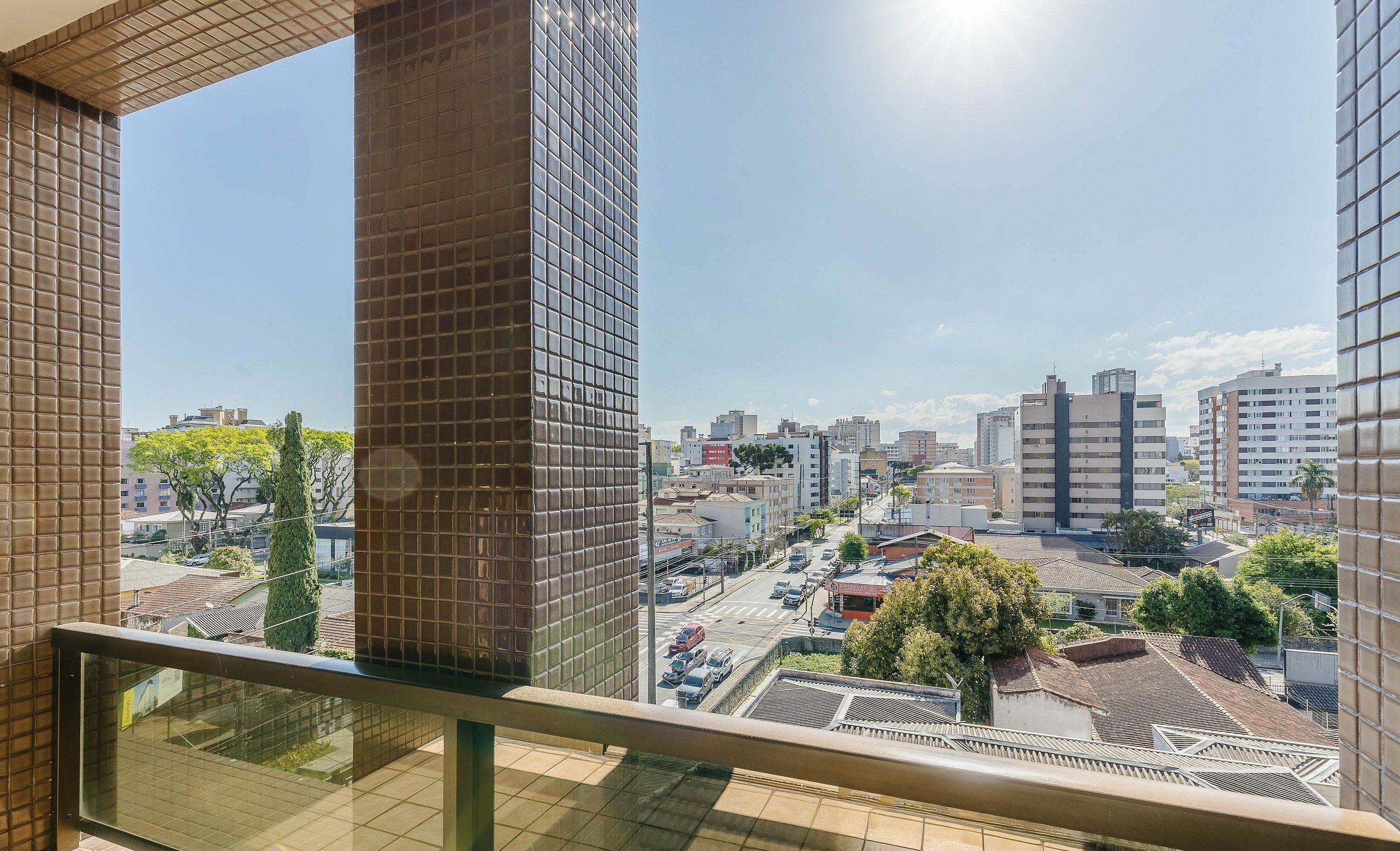 A high-rise building with a clear view of a cityscape, including various buildings and a street with vehicles.