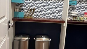 Eine Küche mit einer gemusterten Spritzschutzwand, einem gerahmten Bild und zwei Mülleimern.