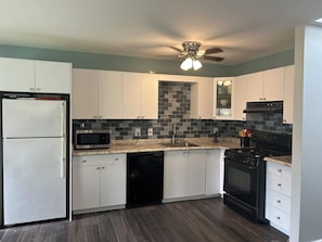 A kitchen with white cabinets, a black stove, a microwave, and a dishwasher. - Cozy 1-bedroom apartment in Private Home in Baiting Hallow with AC (Baiting Hallow)