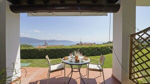 Eine Terrasse im Freien mit Tisch für zwei Personen, mit Blick auf einen malerischen See und entfernte Berge.