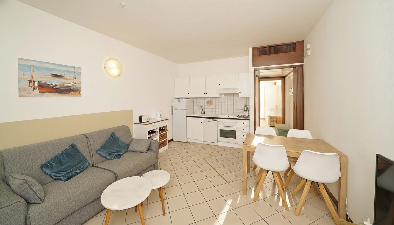 Un espace de vie compact comprenant un coin cuisine, un coin repas et un canapé avec des coussins.