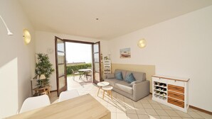 Ein helles Wohnzimmer mit einer Couch, einem Esstisch und einem Weinkühlschrank.