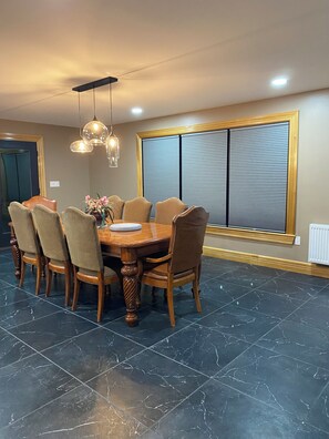 A dining area with a round table, six chairs, and a decorative vase. - Eagle Heights: luxurious Sebago Lake retreat sleeps 8+ (Sebago)