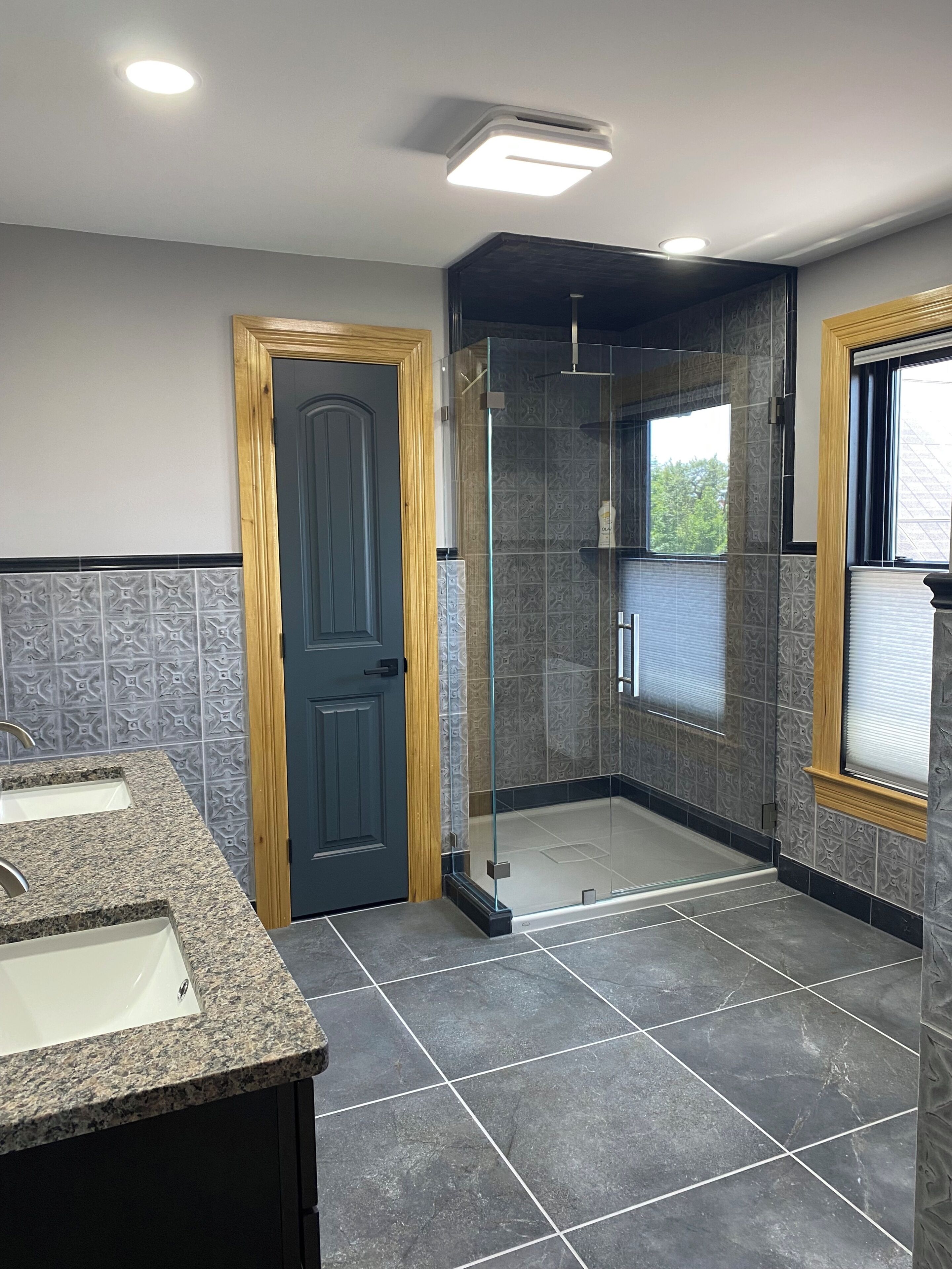 A bathroom with a shower, a sink, and a door.