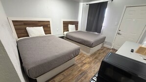 Una habitació d'hotel amb dos llits, una televisió i una porta.