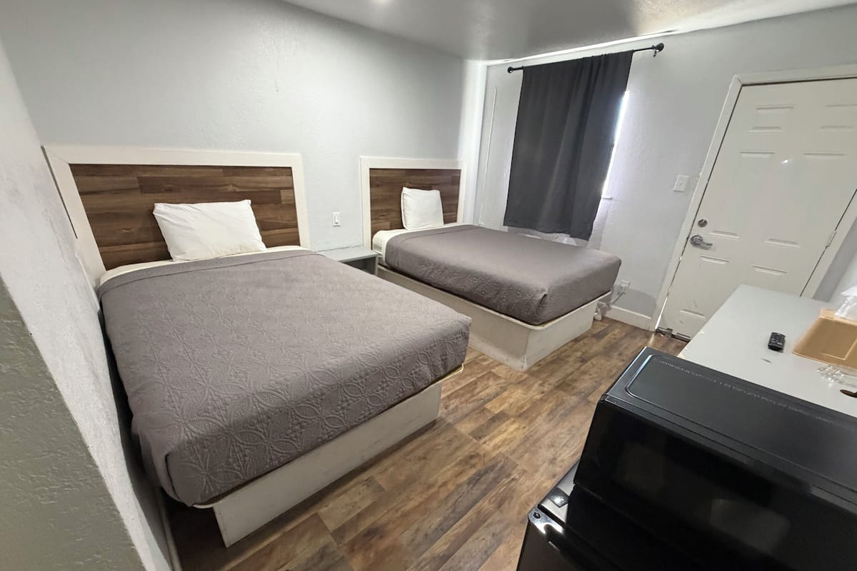 Une chambre d’hôtel avec deux lits, une télévision et une porte.