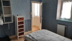 A bedroom with a bed, a wardrobe, a radiator, and a window with curtains. - Gite du bousquet (Cassagnes-Bégonhès)