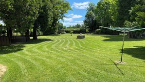 A well-maintained grassy lawn with a stone structure and a clothesline. - Gite du bousquet (Cassagnes-Bégonhès)