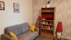 A living room with a grey sofa, a bookshelf, a red lamp, and a framed picture on the wall. - Gite du bousquet (Cassagnes-Bégonhès)