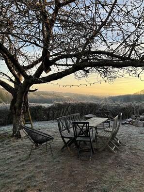 A rustic outdoor dining area with a wooden table and chairs, surrounded by a tree and a view of a distant landscape. - Magnificent fully renovated farmhouse (Verrières)