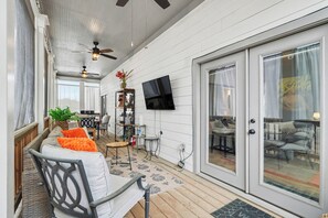 A covered outdoor area with a sofa, chairs, a table, a TV mounted on the wall, and a ceiling fan. - Contemporary new craftsman in the heart of Atlanta! 
FIFA Ready (Atlanta)