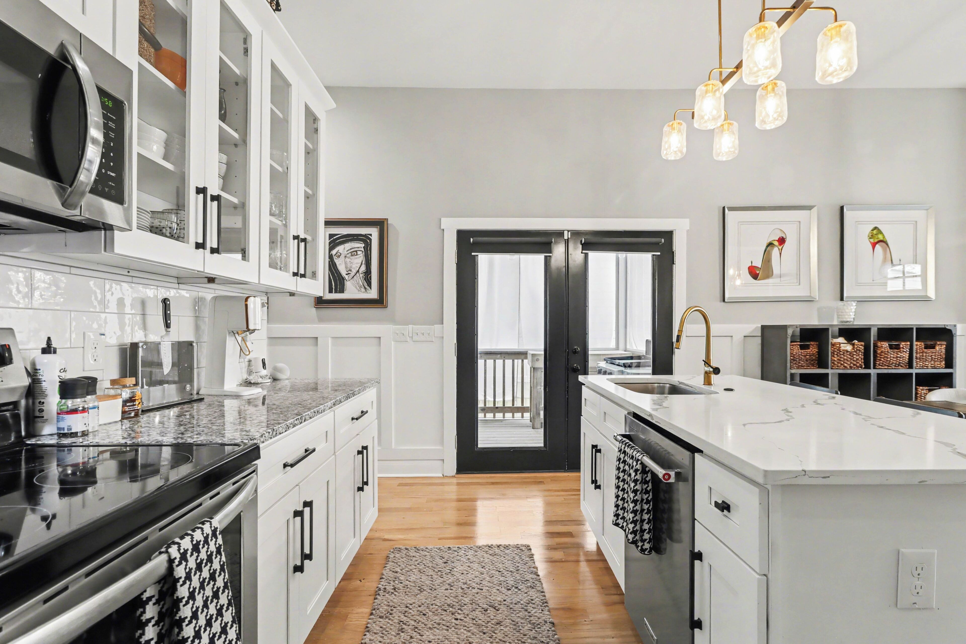 A modern kitchen with white cabinetry, a black stove, and a large island with a sink.