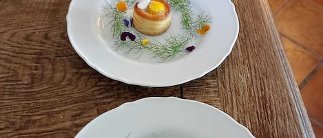 Three white plates with food on a wooden table.