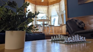 Ein Holztisch mit einem Schachspiel und einem Topfpflanzen im Vordergrund.