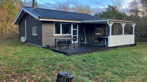 Ett envåningshus med en inglasad veranda, en skorsten och en liten uteplats.