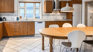 A modern kitchen with wooden cabinets, a stainless steel range hood, and a large window. - Cozy home in Hanstholm with WiFi (Hanstholm)