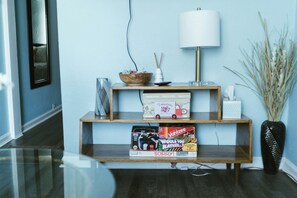 Una sala de estar moderna con una consola de madera, una lámpara blanca, un cuenco decorativo y un florero con cañas.