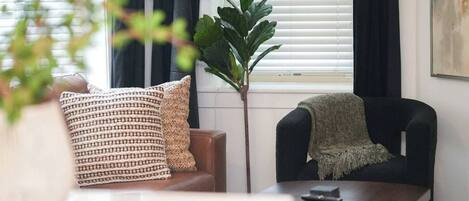 A modern living room with a sofa, a chair, a lamp, and a plant.