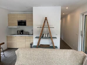 Eine moderne Küche mit Holzausstattung, einem eingebauten Backofen und einer Kaffeemaschine.