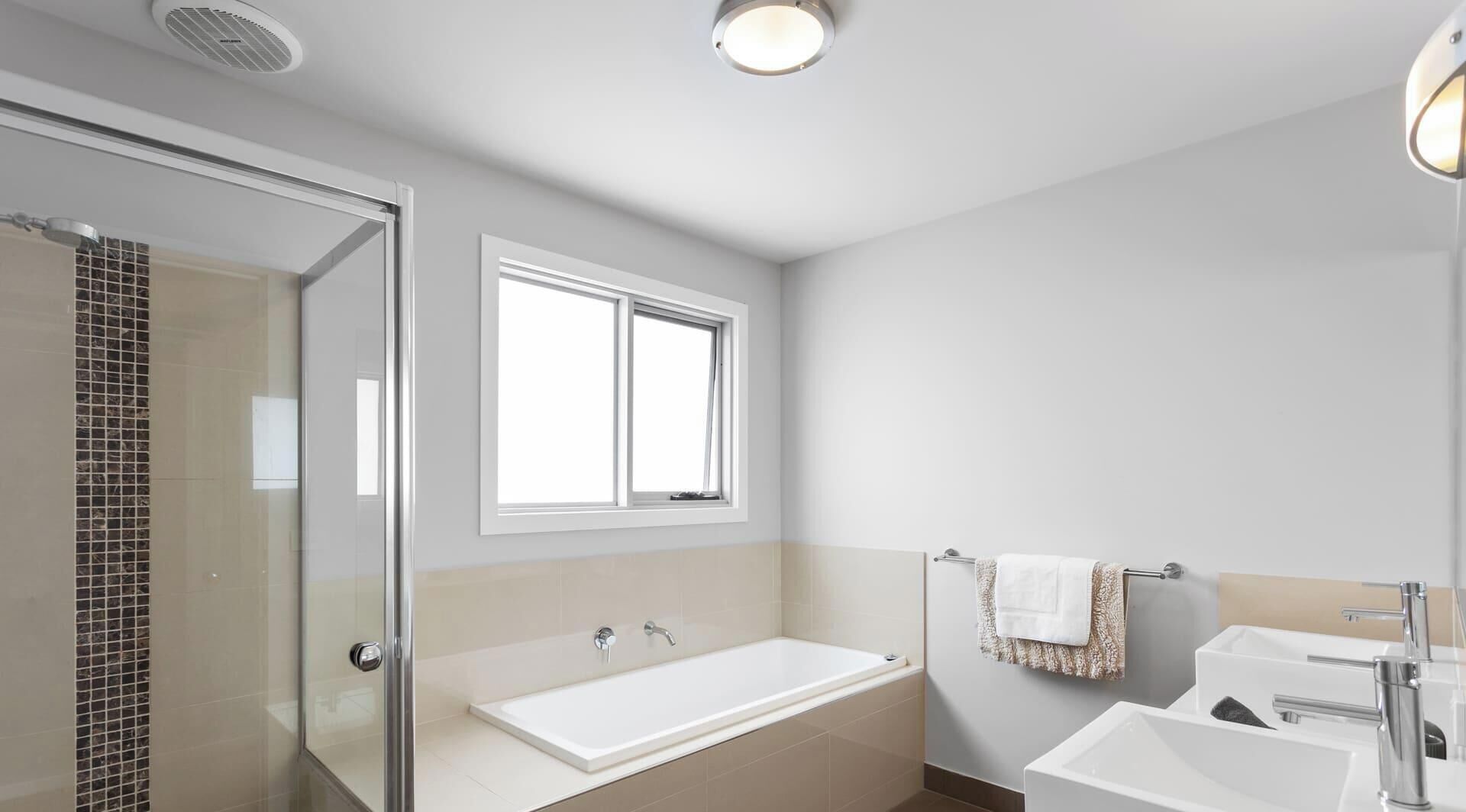 Ein modernes Badezimmer mit Duschkabine aus Glas, einer freistehenden Badewanne und einem Waschtisch mit Spüle und Spiegel.