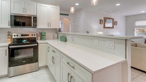 A modern kitchen with white cabinetry, stainless steel appliances, and pendant lighting. - Clearwater Beach Home w/ Private Pool & Pool Table (Clearwater)