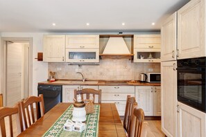 Una cocina moderna con armarios de madera, una mesa de comedor con sillas, un microondas y un lavavajillas.