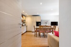 Una cocina moderna con armarios de madera, una mesa de comedor con sillas y un televisor de pantalla plana.