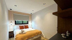A modern bedroom with a bed, bedside tables, a window, and a wooden shelf with decorative items.