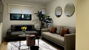 Ein modernes Wohnzimmer mit grauem Sofa, einem runden Couchtisch und einem großen Spiegel an der Wand.