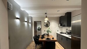Une cuisine moderne dotée d’un îlot central, de meubles de couleur sombre et d’un réfrigérateur en acier inoxydable.