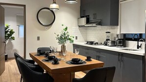 Une cuisine moderne dotée d’un îlot central, de luminaires suspendus et d’un coin repas avec des chaises.