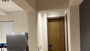 Une cuisine moderne avec un réfrigérateur en acier inoxydable, une porte en bois et un plancher de couleur claire.