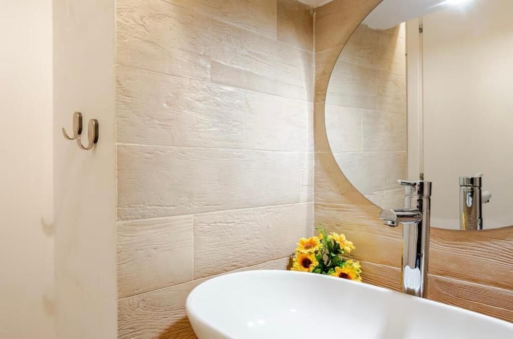 A modern bathroom with a freestanding bathtub, a large mirror, and a wooden vanity.