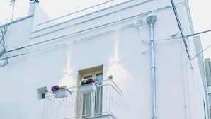 A white building with a balcony, a window with decorative bars, and a visible door. - NAP25GUESTHOUSE (Polignano a Mare)