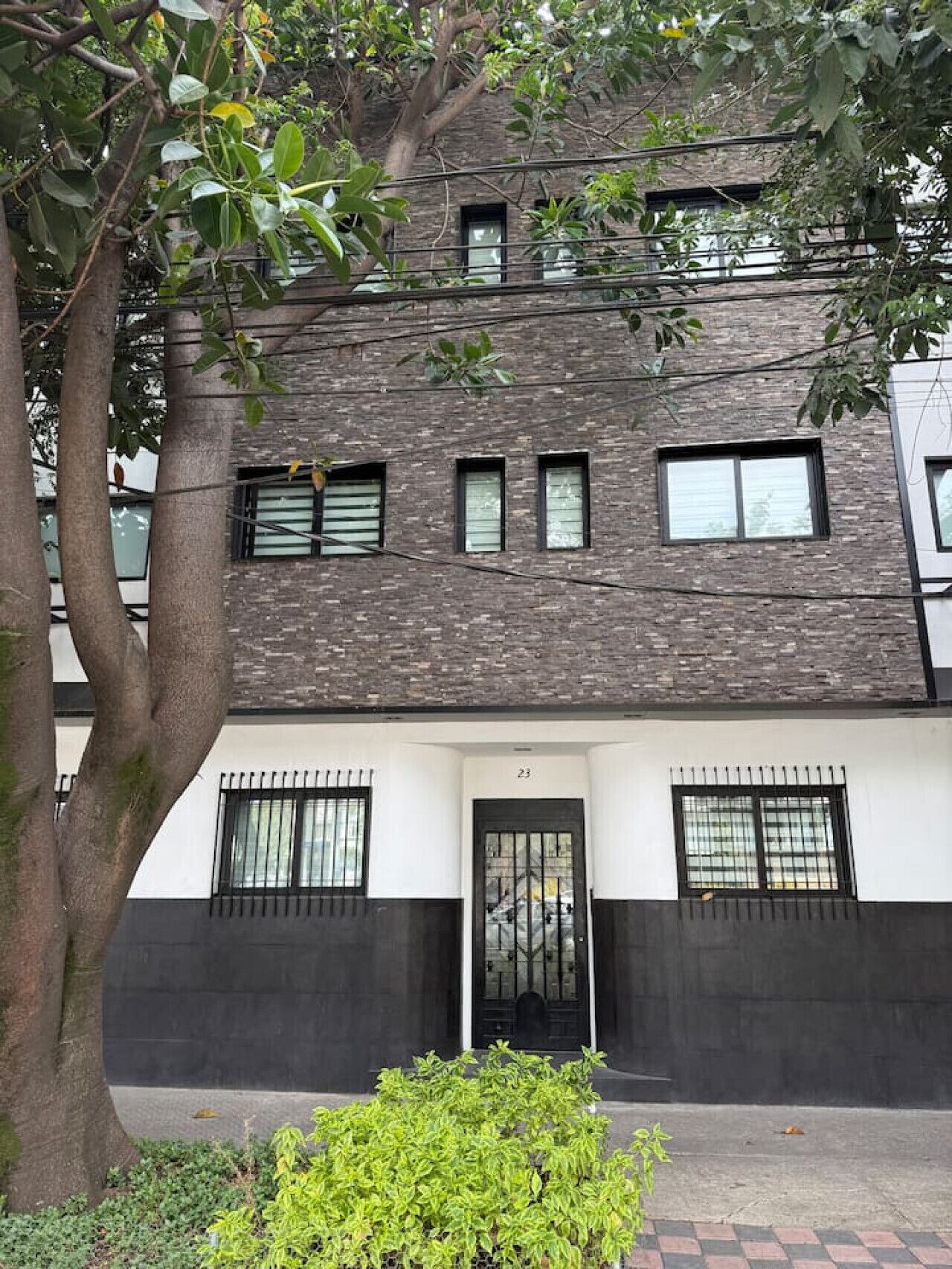 A modern building with a brick facade, multiple windows, and a black door.