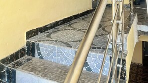 Un escalier avec une rampe métallique et une fenêtre avec des barreaux en métal.