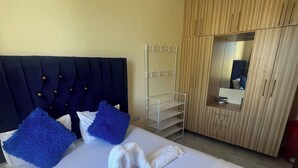 Une chambre d’hôtel équipée d’un lit, d’une armoire, d’un miroir et d’un ventilateur de plafond.