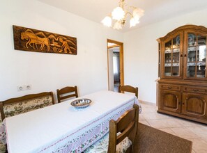 A dining area with a table set for four, a wooden cabinet with glass doors, and a wall-mounted sculpture. - Comfort Villa Roza in Umag - 5 Bedroom With Pool (Umag)