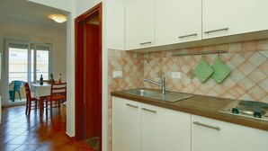 A compact kitchen with white cabinets, a wooden countertop, and a tiled backsplash. - One Bedroom Apartment with Terrace (Savudrija)